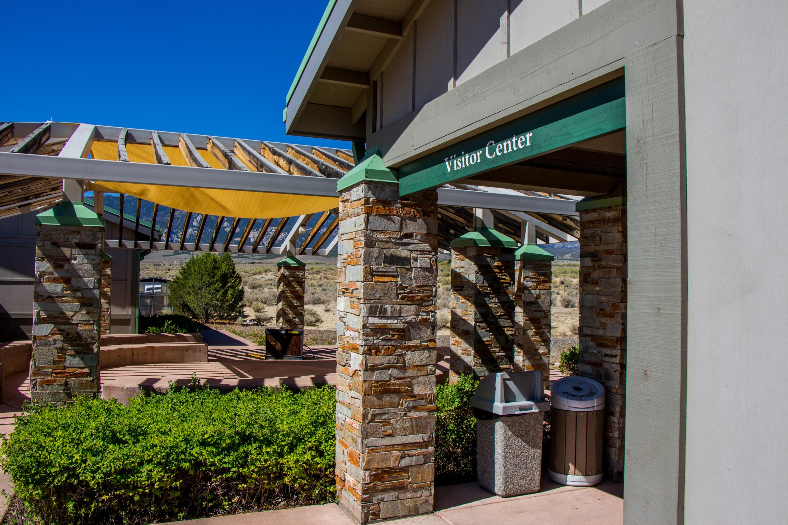 Great Basin National Park Visitor Center exterior with stone pillars and shaded walkway under a blue sky.