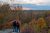 Two people stand on a rocky overlook in fall colors, watching a sunset over the forested valley in Cuyahoga Valley National Park.