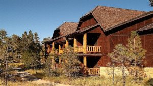 Rustic wooden lodge with multiple balconies and weathered siding sits along a pine-lined trail at Bryce Canyon National Park