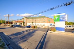 Exterior view of a hotel near Carlsbad Caverns National Park, with a blue sky and parking lot in front.