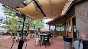 Outdoor restaurant patio under tan shade sails in Capitol Reef National Park.