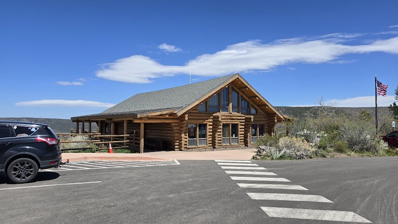 South Rim Visitor Center at Black Canyon of the Gunnison National Park, a wood-log lodge-style facility beside a paved lot.