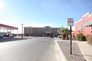 Hotel exterior at a Carlsbad lodging area near Carlsbad Caverns National Park, with a no-parking sign and palm trees.