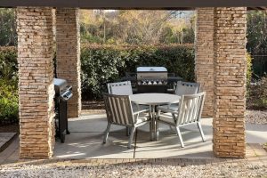 Outdoor covered patio with round dining table, metal chairs, and built-in grills near Congaree National Park.