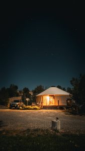 Nighttime view of a warmly lit yurt lodging near Capitol Reef National Park beneath a star-filled desert sky.