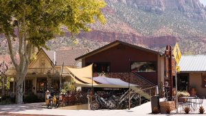 Gift shop and bike rental area in Zion National Park under a shaded canopy, with bikes parked outside.