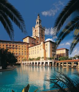 Pool at a historic Coral Gables hotel near Biscayne National Park, framed by palm fronds under a bright blue sky.