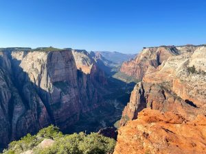 East Mesa Trailhead to Observation Point overlook along Zion Canyon, dramatic layered cliffs and blue sky.