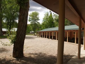 Island Acres Resort Motel at Black Canyon Of The Gunnison National Park features a row of rustic cabins along a shaded gravel lot.