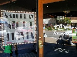 Glass storefront with a large Saturday Night Trivia poster and warm wood trim at a park tavern in Black Canyon Of The Gunnison National Park.