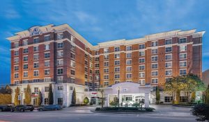 Hotel exterior in Columbia near Congaree National Park, a brick-front building with white accents under a blue sky.
