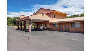 Lodge-style motel exterior near Black Canyon Of The Gunnison National Park, a brick-and-tile building with a wide covered entry and parking lot.