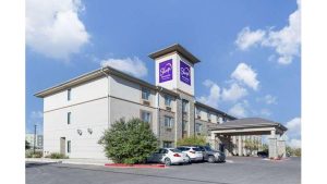 Exterior of lodging near Carlsbad Caverns National Park, a multi-story hotel with a purple sign and blue sky.