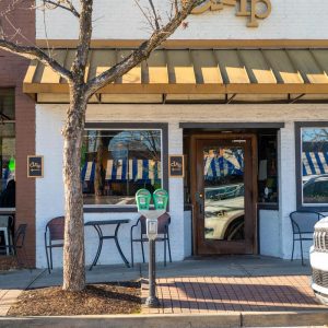 Cafe storefront with striped awnings and outdoor seating along a sidewalk near Congaree National Park.