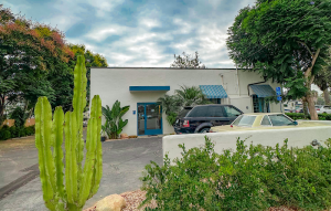 Lodging building with blue awnings and a parking lot in Channel Islands National Park, surrounded by palms and cacti.