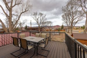 Outdoor dining deck at a lodge near Capitol Reef National Park overlooks a distant town and desert canyon.