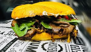 Capitol Reef National Park dining area features a loaded burger with greens and onions on a toasted bun from El Charro Negro restaurant.