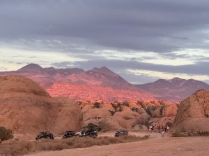 Hummer and ATV tour vehicles sit along a dusty canyon road beneath red rock formations in Canyonlands National Park.