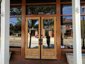 Storefront entrance in Congaree National Park reflected in glass doors, with wooden framing and street scene.