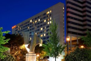 Downtown Columbia hotel exterior lit at night with trees and modern glassy architecture against a dark sky.