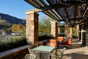 Outdoor hotel patio with stone columns and glass tables under a decorative trellis in Channel Islands National Park area.