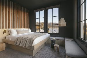 Lodge bedroom interior in Channel Islands National Park near Santa Barbara, with a king bed, wood accent wall, and large windows.