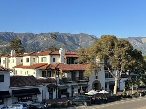 Montecito Inn exterior along a sunny Channel Islands National Park street with red-tiled roofs and mountains.