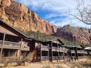 Zion Lodge exterior along the canyon road in Zion National Park, with towering red cliffs above.