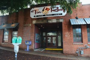 Brick restaurant building entrance at Congaree National Park, with a sign indicating live music, seen under leafy trees.