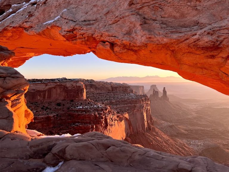 Mesa Arch Trailhead overlook in Canyonlands National Park framed by the glowing sandstone arch at sunrise.