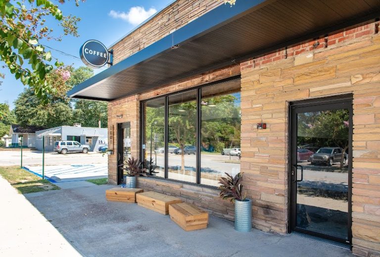 Café storefront along a brick building in Congaree National Park area, with large windows and wooden planters outside.