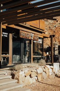 Restaurant exterior at Zion National Park with rustic wood siding, glass walls, and a rock-strewn landscape.