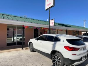 Gift shop storefront along a parking area at Carlsbad Caverns National Park, with a white SUV in front and colorful decorations along the awning.