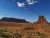 Desert red rock formations at Arches National Park, with a flat-topped mesa left and a tall butte right under a blue sky.