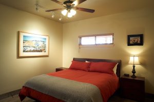 Lodge bedroom with red bedding and a ceiling fan in Capitol Reef National Park.