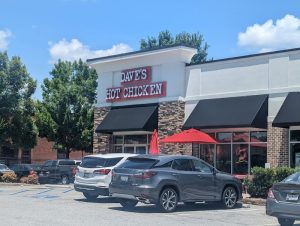 Restaurant storefront exterior near Congaree National Park with black awnings and red umbrellas.