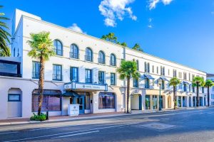 Historic hotel façade with arched windows and palm trees along a sunny street in Channel Islands National Park area.