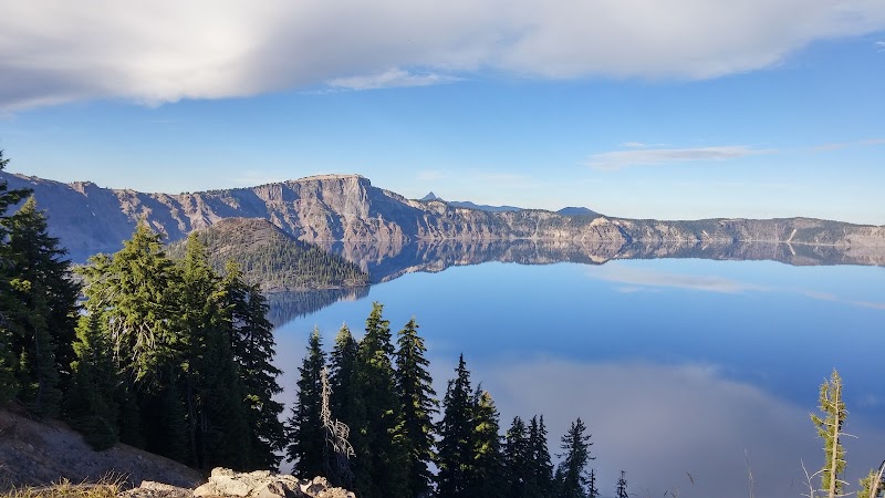Crater Lake's deep blue caldera and cliff walls reflect on the glassy surface from the Rim viewpoint in Crater Lake National Park.