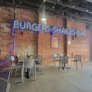 Interior of a brick-walled restaurant in Congaree National Park with casual seating and neon decor.