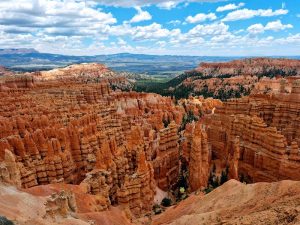 Sunset Point overlook in Bryce Canyon National Park features towering orange hoodoos and layered cliffs under a bright blue sky.