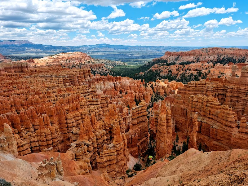Sunset Point overlook in Bryce Canyon National Park features towering orange hoodoos and layered cliffs under a bright blue sky.