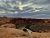 Sunset over red rock cliffs in Arches National Park, with a winding river cutting through canyon walls.