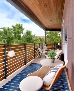 Balcony lounge on a lodge balcony in Canyonlands National Park, Moab area, with wooden railing and view of green trees.