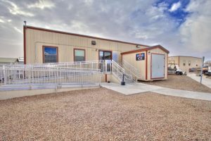 Carlsbad Lodge hospitality building at Carlsbad Caverns National Park, with a gravel lot, wheelchair ramp, and a small entrance sign.