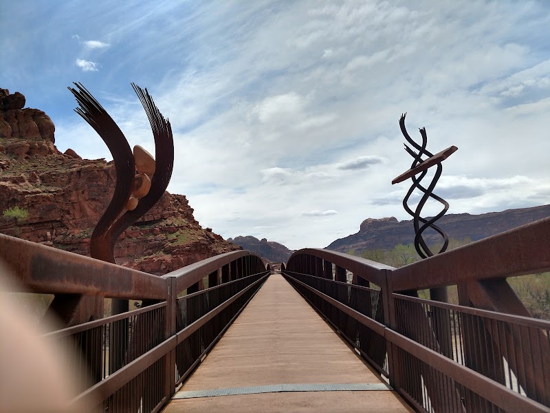 Bridge at Arches National Park with rusted rails and twisting metal sculptures over a rock canyon.