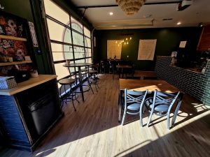 Interior of a cafe in Bryce Canyon National Park with dark green walls and wooden floor, seating and a brick counter visible.