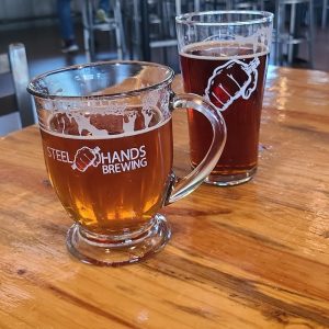 Two beer glasses on a wooden table inside a tasting room at Congaree National Park.