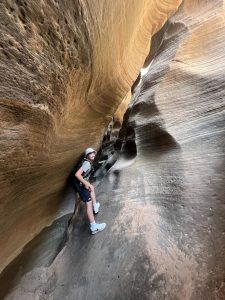 Hiker navigating the narrow sandstone walls along Keyhole Canyon in Zion National Park.