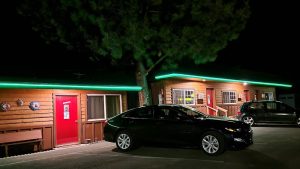 Lodging exterior with red doors and green neon trim along cabin row at night in Crater Lake National Park