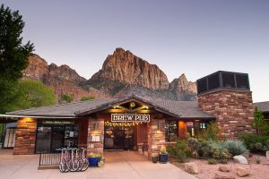 Zion Canyon Brew Pub at Zion National Park sits beneath towering red rock formations.